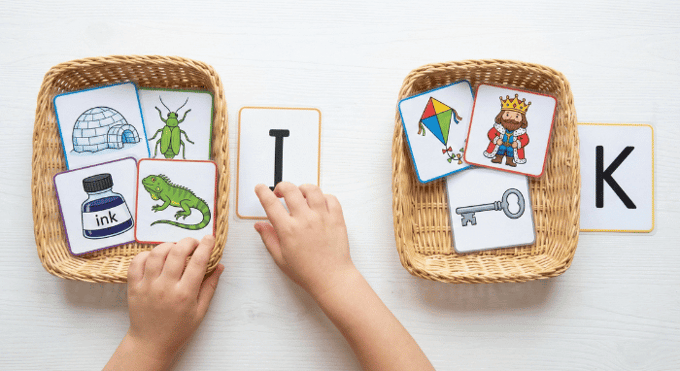Preschooler sorting picture cards by beginning sound for letter K phonics activity