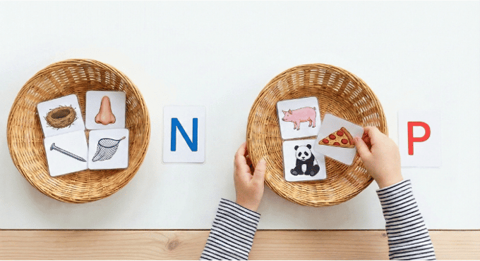 Preschooler sorting picture cards by beginning sound for letter N phonics activity
