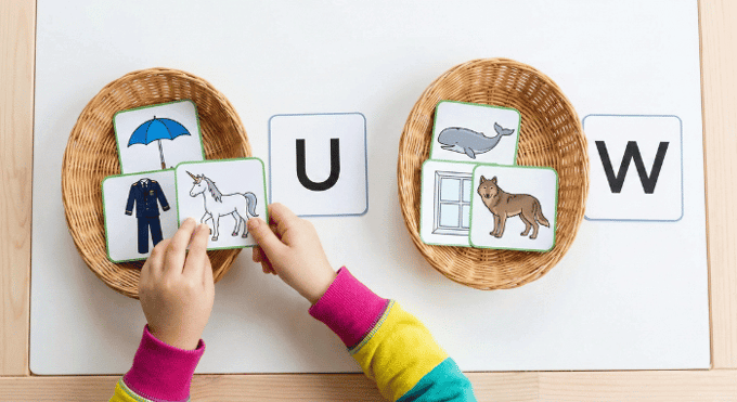Preschooler sorting picture cards by beginning sound for letter W phonics activity