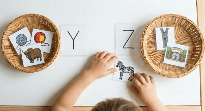 Preschooler sorting picture cards by beginning sound for letter Y phonics activity