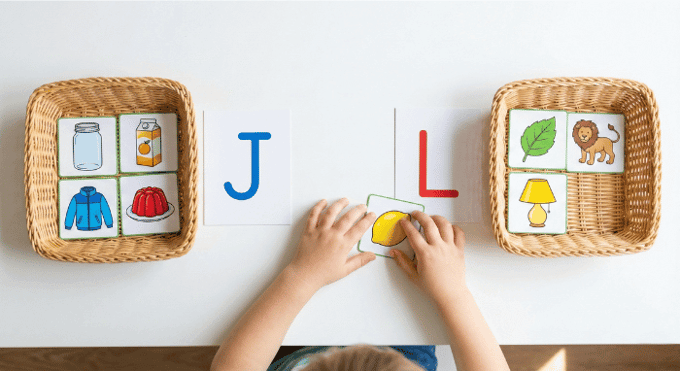 Preschooler sorting picture cards by beginning sound for letter J phonics activity
