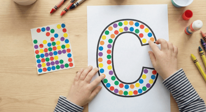 Child filling letter C outline with colorful stickers for fine motor practice