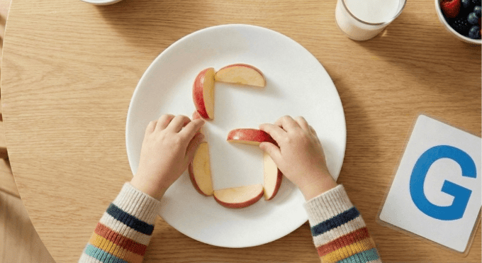 Preschooler forming letter G shape with apple slices for edible learning activity