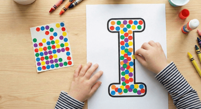 Child filling letter I outline with colorful stickers for fine motor practice