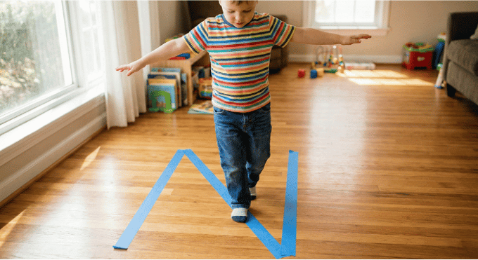 Preschooler hopping on letter N made with tape on floor for active learning