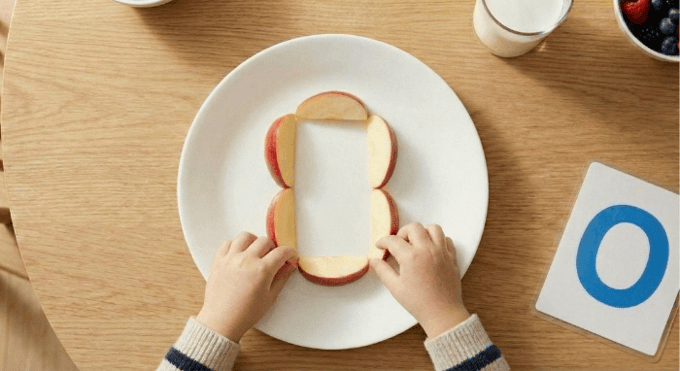 Preschooler forming letter O shape with apple slices for edible learning activity