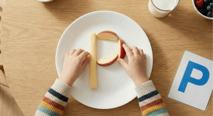 Preschooler forming letter P shape with cheese stick and apple slices for edible learning activity
