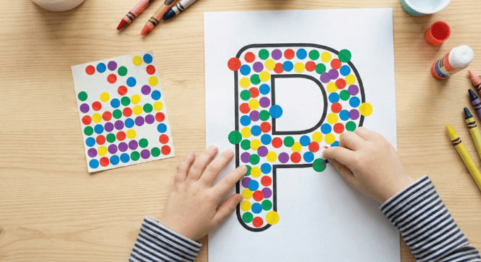 Child filling letter P outline with colorful stickers for fine motor practice