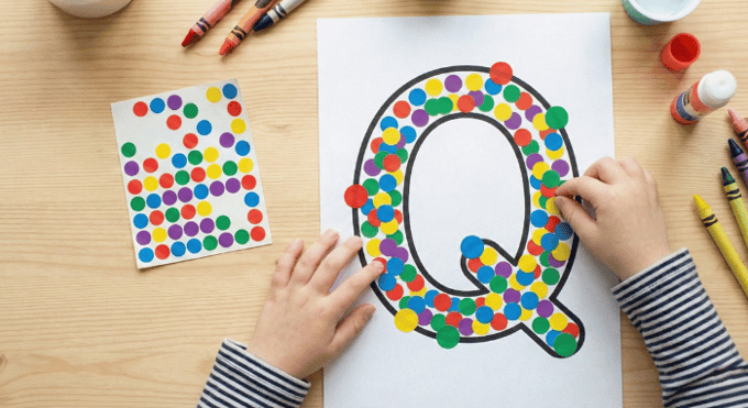 Child filling letter Q outline with colorful stickers for fine motor practice