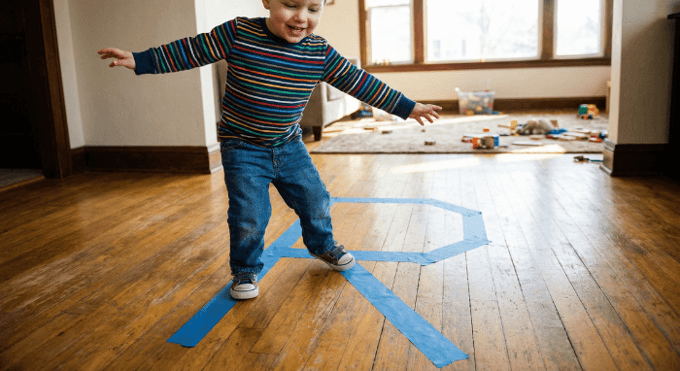 Preschooler hopping on letter R made with tape on floor for active learning