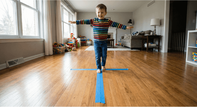 Preschooler hopping on letter T made with tape on floor for active learning