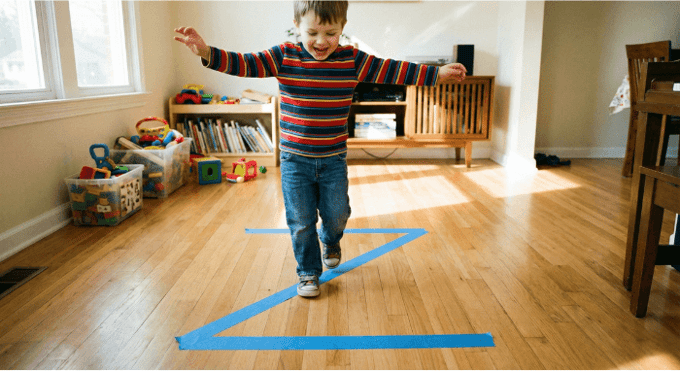 Preschooler hopping on letter Z made with tape on floor for active learning