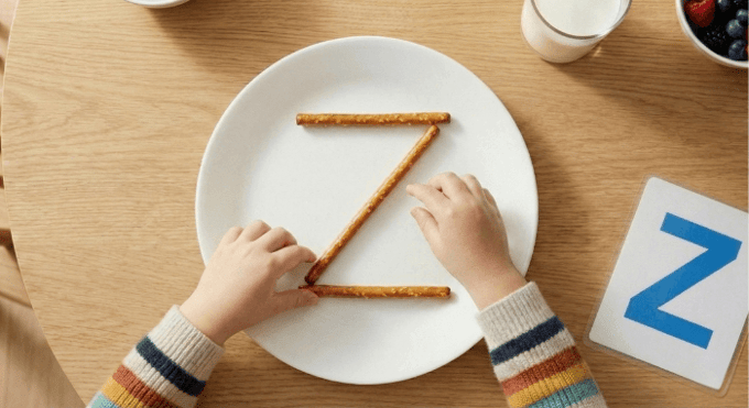 Preschooler forming letter Z shape with pretzel sticks for edible learning activity