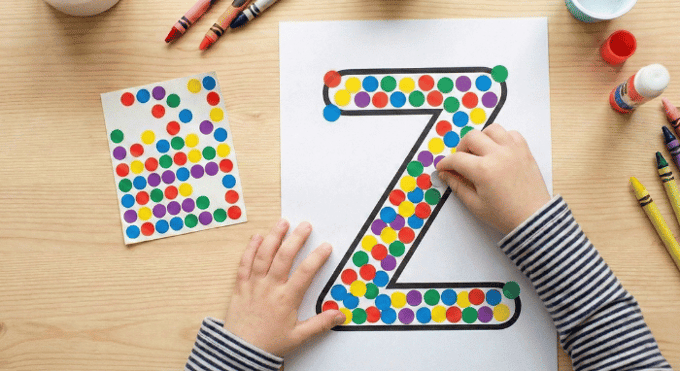 Child filling letter Z outline with colorful stickers for fine motor practice