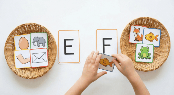 Preschooler sorting picture cards by beginning sound for letter E phonics activity