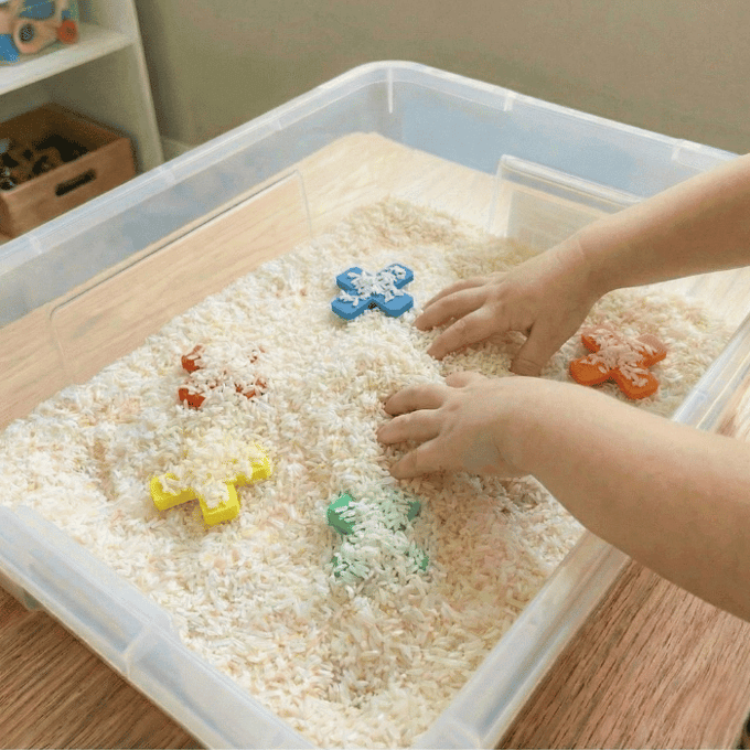 Preschool sensory bin activity with hands finding craft foam letter Xs in rice