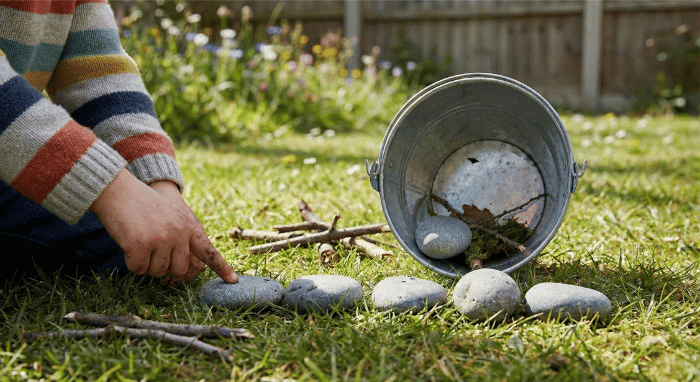 Child counting collected rocks and sticks from nature walk sorted into groups on grass