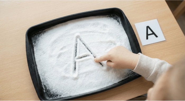 Letter A activities: preschooler using salt tray for tactile letter tracing practice